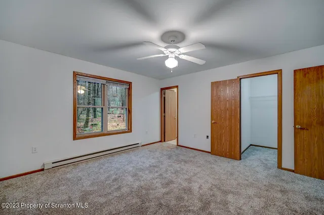 an empty room with chandelier fan and windows