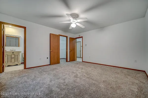 an empty room with closet and a ceiling fan