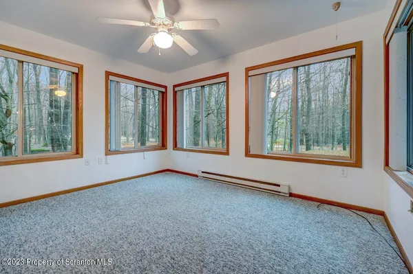 a view of an empty room with window and chandelier fan