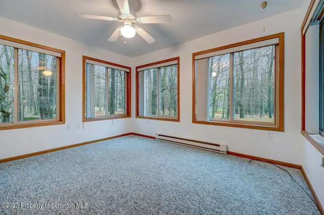 a view of an empty room with window and chandelier fan