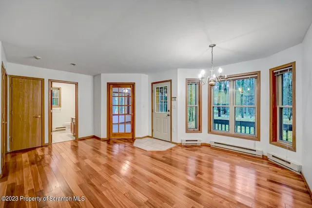 a view of an empty room with window and wooden floor
