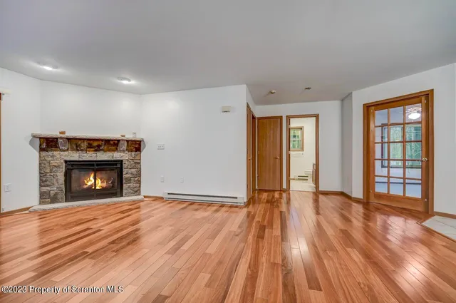 a view of an empty room with wooden floor fireplace and a window