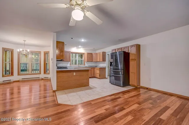 a large kitchen with kitchen island a stove a refrigerator cabinets and a wooden floor
