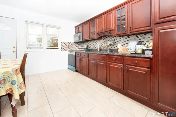 a kitchen with stainless steel appliances granite countertop a sink a stove cabinets and empty room