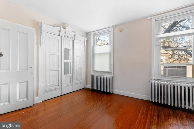 a view of empty room with wooden floor and fan