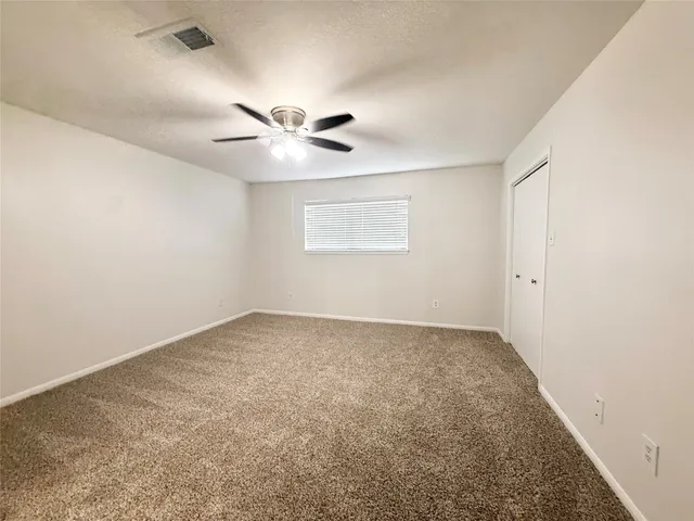 an empty room with a chandelier fan and windows