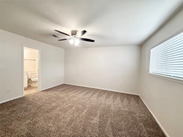 an empty room with windows and fan
