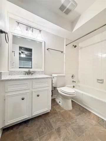 a bathroom with a granite countertop toilet a sink and a bathtub