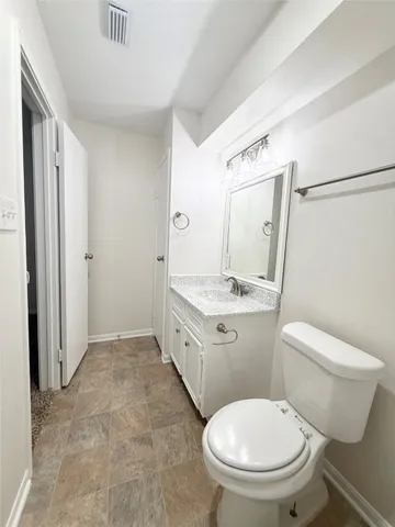 a bathroom with a granite countertop toilet a sink and a mirror