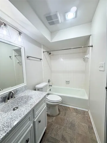 a bathroom with a granite countertop sink a toilet a mirror and shower