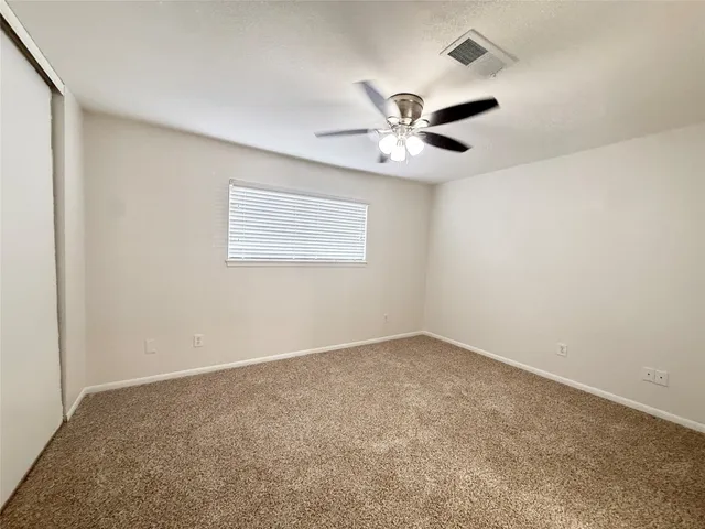 an empty room with windows and fan