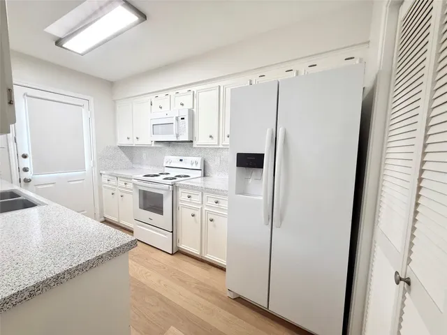 a kitchen with white cabinets and white appliances