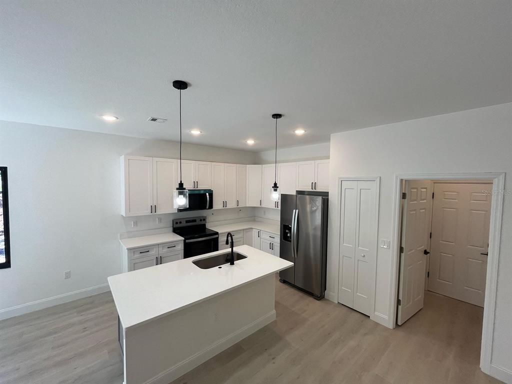 1597 Kerman Street North Port, FL 34288 - Photo 10 of 26 a kitchen with stainless steel appliances kitchen island granite countertop a refrigerator and a stove top oven