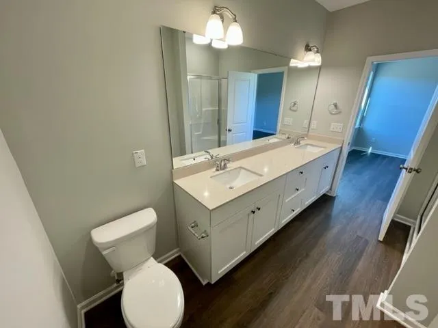 a spacious bathroom with a double vanity sink toilet and a mirror