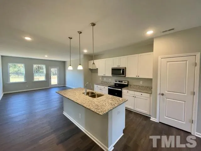 a kitchen with stainless steel appliances granite countertop a sink dishwasher a stove and a refrigerator with wooden floor