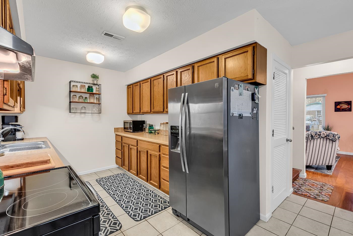 724 Juniper Drive, Unit B Surfside Beach, SC 29575 - Photo 12 of 36 Kitchen with stainless steel appliances, brown cabinets, light countertops, light tile patterned floors, and exhaust hood