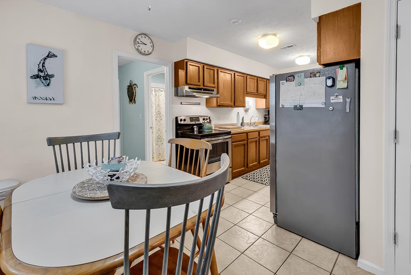 724 Juniper Drive, Unit B Surfside Beach, SC 29575 - Photo 8 of 36 Kitchen featuring brown cabinetry, stainless steel appliances, under cabinet range hood, and light tile patterned floors