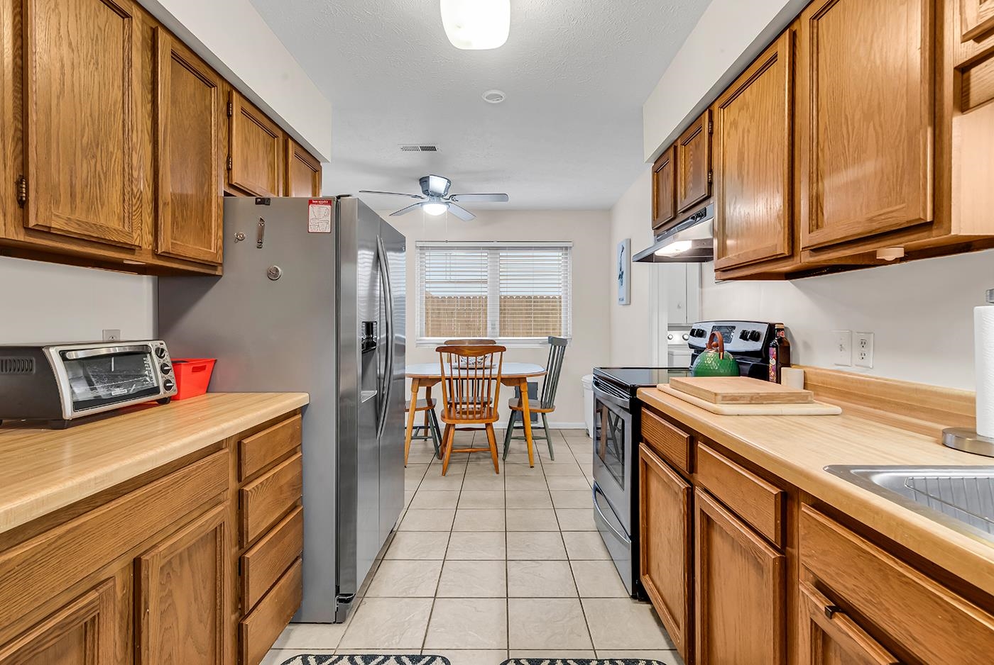 724 Juniper Drive, Unit B Surfside Beach, SC 29575 - Photo 10 of 36 Kitchen featuring stainless steel appliances, brown cabinets, light countertops, ceiling fan, and under cabinet range hood