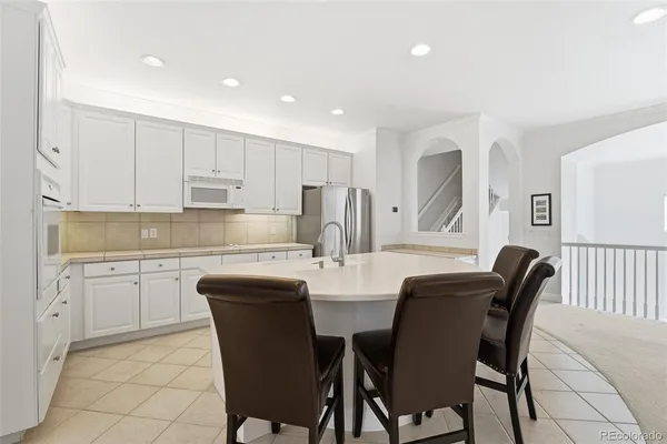 a kitchen with stainless steel appliances granite countertop a table and chairs in it