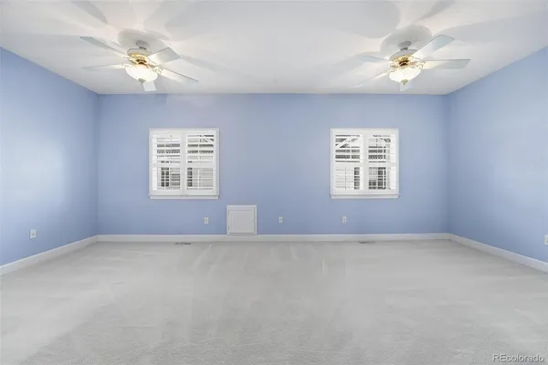 an empty room with windows and fan