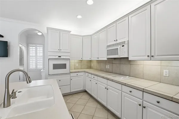 a white kitchen with sink and cabinets