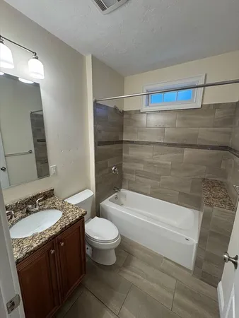 a bathroom with a granite countertop bathtub sink vanity mirror and toilet