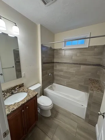 a bathroom with a granite countertop bathtub sink vanity mirror and toilet