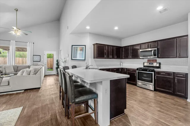 a living room with stainless steel appliances kitchen island granite countertop wooden floor a dining table and chairs