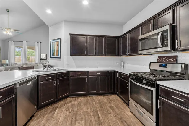 a kitchen with stainless steel appliances granite countertop wooden cabinets stove top oven and sink