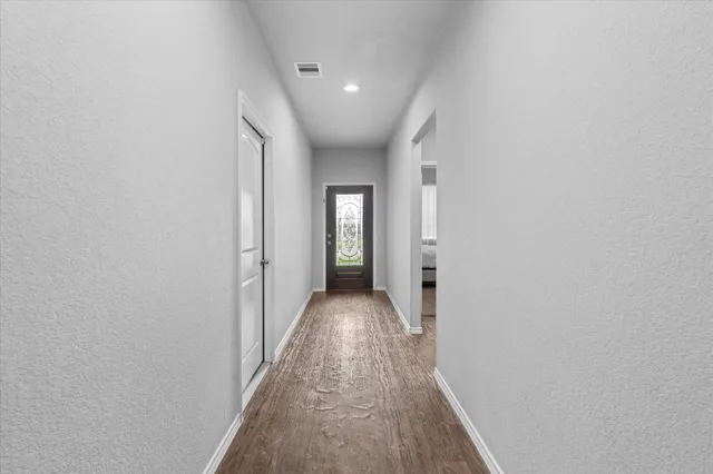 a view of a hallway with wooden floor and a bathroom
