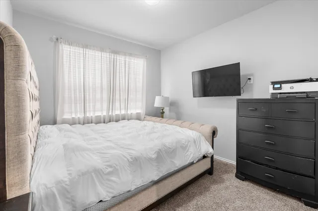 a bedroom with a bed and a flat tv screen on a dresser