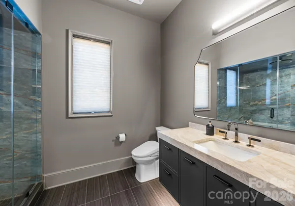 a bathroom with a granite countertop sink a toilet and a mirror