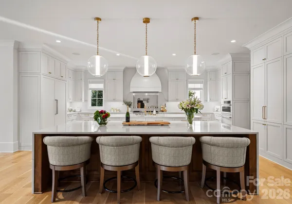 a kitchen with stainless steel appliances kitchen island granite countertop a dining table chairs and white cabinets