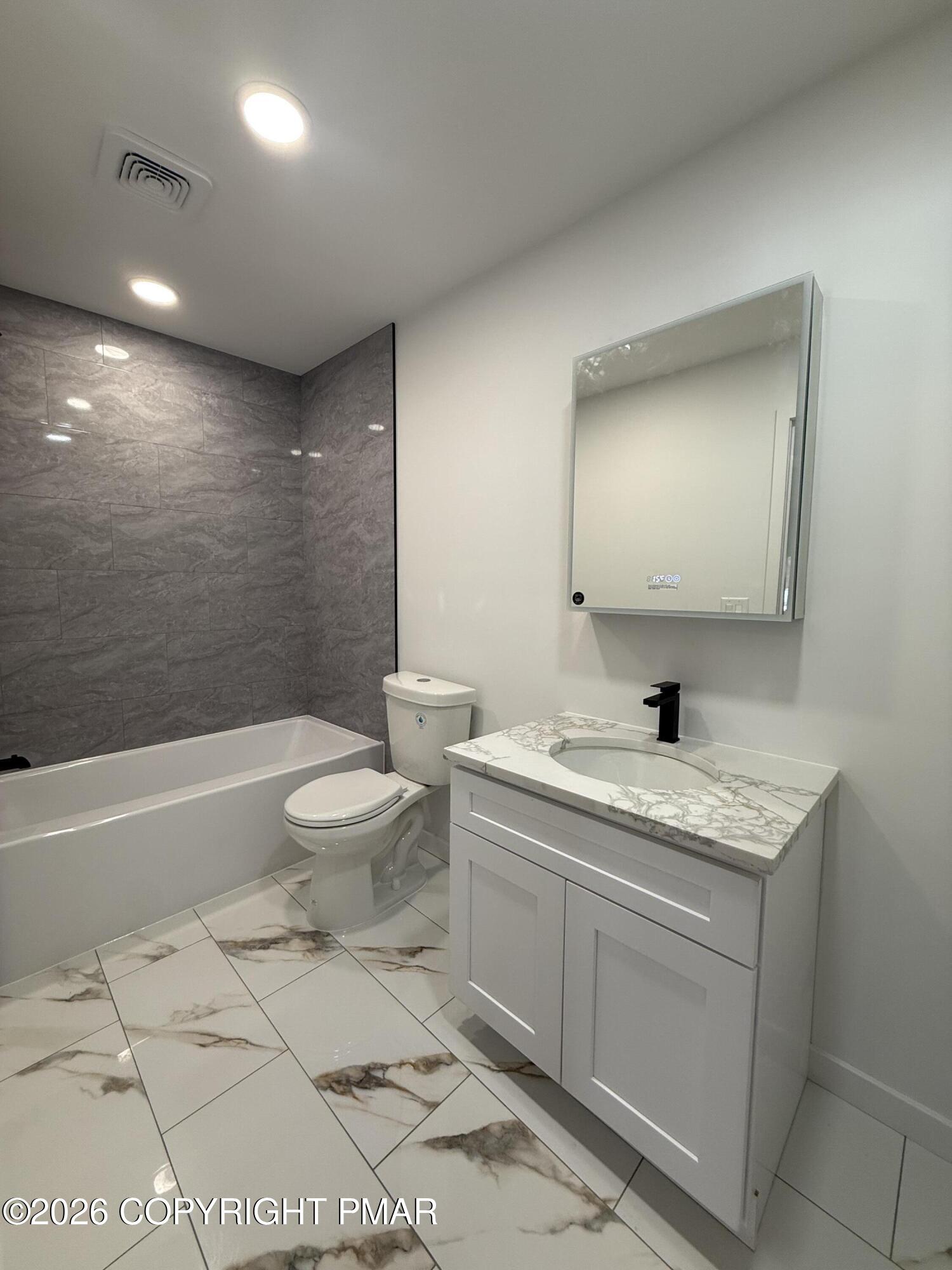 104 Condor Drive, Unit 1 Tamiment, PA 18371 - Photo 22 of 23 a spacious bathroom with a granite countertop toilet a sink and a mirror