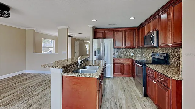 a kitchen with stainless steel appliances granite countertop wooden cabinets stove and granite counter top