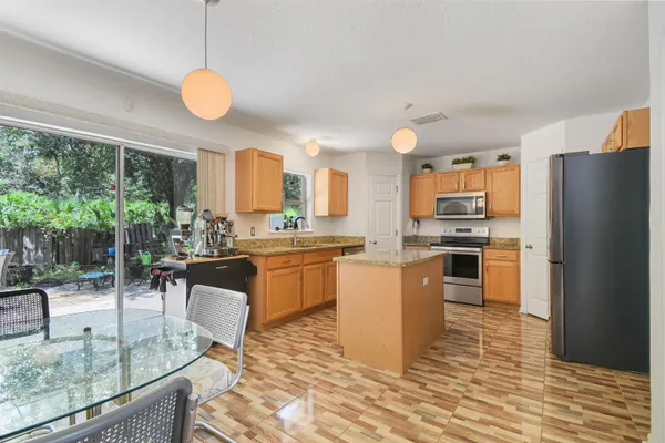 a kitchen with stainless steel appliances granite countertop a stove top oven a sink dishwasher a dining table and chairs with wooden floor