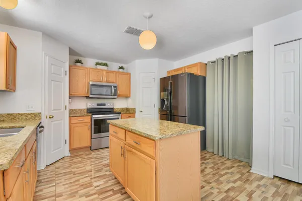a kitchen with granite countertop a refrigerator stove top oven and sink