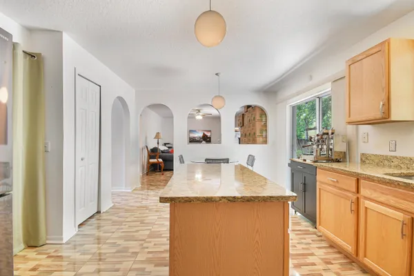 a large kitchen with granite countertop a large counter top a sink cabinets and stainless steel appliances