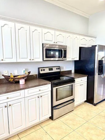 a kitchen with stainless steel appliances granite countertop white cabinets a stove a microwave and a sink