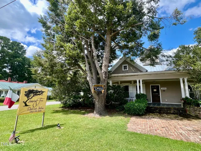 a front view of a house with a garden and tree