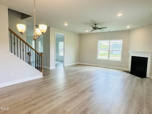 an empty room with wooden floor ceiling fan and windows