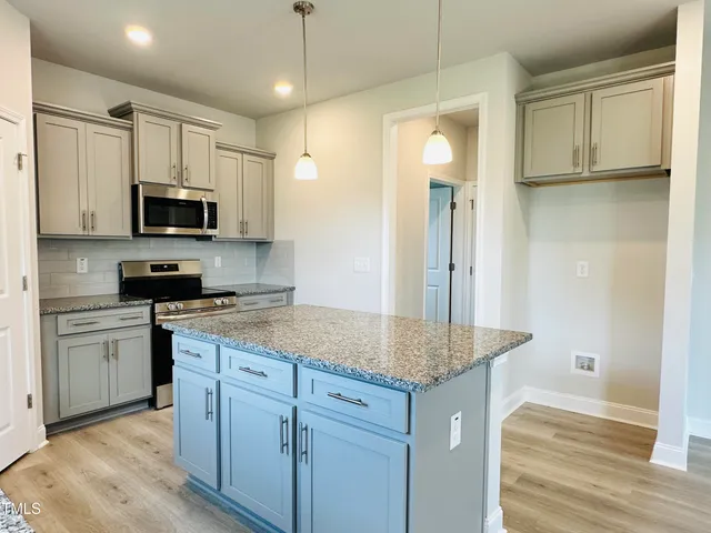 a kitchen with granite countertop a sink a stove and refrigerator