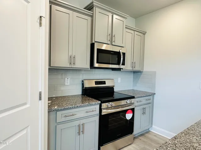 a kitchen with stainless steel appliances granite countertop white cabinets granite counter tops and a window
