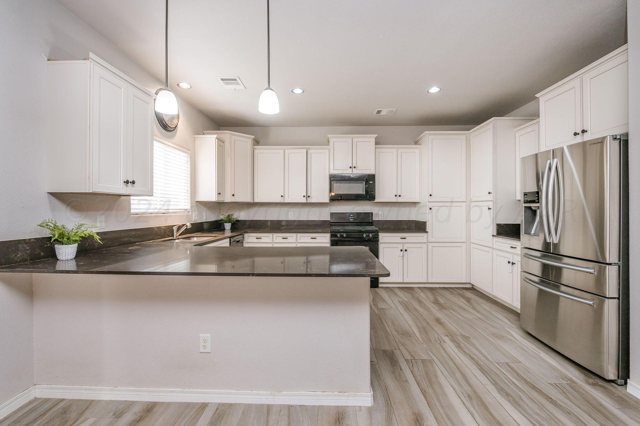 1201 Cabernet Way Amarillo, TX 79124 - Photo 4 of 18 a kitchen with stainless steel appliances granite countertop a sink a stove a refrigerator and island with wooden floor
