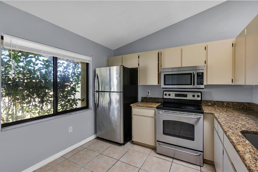 3701 Spring Land Drive Orlando, FL 32818 - Photo 6 of 21 a kitchen with white cabinets stainless steel appliances and a window