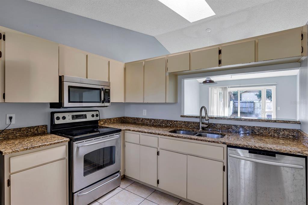 3701 Spring Land Drive Orlando, FL 32818 - Photo 7 of 21 a kitchen with stainless steel appliances granite countertop a sink stove oven a sink with cabinets and wooden floor