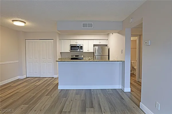 a kitchen with wooden floors and white cabinets