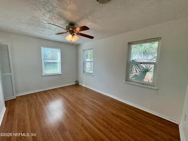 a view of an empty room with wooden floor and a window
