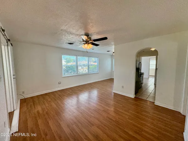 an empty room with wooden floor and windows