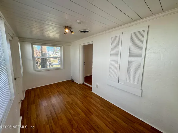 a view of empty room with wooden floor and fan